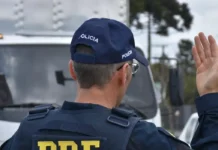Feriado de Nossa Senhora Aparecida regista 68 mortes nas estradas Agente da Polícia Rodoviária Federal de costas, a sinalizar com a mão para orientar o trânsito rodoviário.
