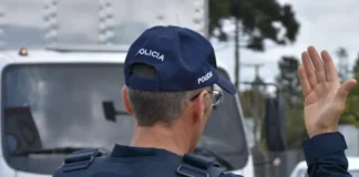 Feriado de Nossa Senhora Aparecida regista 68 mortes nas estradas Agente da Polícia Rodoviária Federal de costas, a sinalizar com a mão para orientar o trânsito rodoviário.