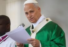 O Papa Leão XIV envergando paramentos litúrgicos verdes enquanto lê um documento ao microfone durante uma cerimónia religiosa.