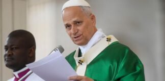 O Papa Leão XIV envergando paramentos litúrgicos verdes enquanto lê um documento ao microfone durante uma cerimónia religiosa.