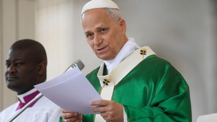 O Papa Leão XIV envergando paramentos litúrgicos verdes enquanto lê um documento ao microfone durante uma cerimónia religiosa.