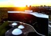 Vista aérea do edifício do Tribunal Superior Eleitoral (TSE) em Brasília, exibindo a sua arquitetura com fachada em curva negra e branca sob a luz de um pôr do sol.