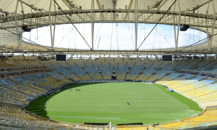 Estádio do Maracanã preparado para partida de futebol Vista panorâmica interna do estádio do Maracanã, com o gramado verde em destaque e as arquibancadas vazias, sob o teto coberto da arena.