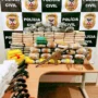 Polícia apreende 140 kg de drogas e fuzil após perseguição em Nova Mamoré Mesa exibindo diversos pacotes de drogas empilhados, ladeados por seis revólveres, pistolas, um fuzil e dezenas de munições, com um painel da Polícia Civil ao fundo.