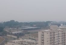 Vista aérea de Manaus sob um céu cinzento e totalmente encoberto por uma densa camada de fumaça, dificultando a visibilidade dos prédios e da vegetação.