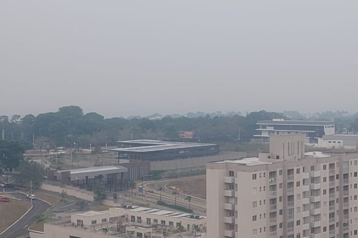 Fumaça encobre a cidade de Manaus Vista aérea de Manaus sob um céu cinzento e totalmente encoberto por uma densa camada de fumaça, dificultando a visibilidade dos prédios e da vegetação.