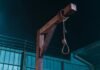 Irã condena 106 manifestantes à morte e já executa 35, aponta ONG Estrutura de madeira formando uma forca com uma corda amarrada, montada à noite contra um fundo escuro e uma cerca.