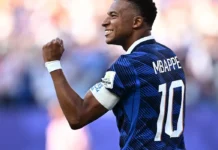 Fifa: um em cada cinco ataques virtuais na Copa do Mundo foi racista O jogador Mbappé sorrindo e comemorando em campo, vestindo a camisa azul da seleção francesa de futebol.