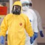 Ilustração laboratorial ou imagem de profissional de saúde com vestimenta de proteção examinando amostras biológicas em área de contenção epidemiológica.