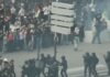 Multidão de jovens estudantes e manifestantes reunidos em uma grande avenida na França, segurando faixas e cartazes durante um protesto diurno.