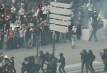 Multidão de jovens estudantes e manifestantes reunidos em uma grande avenida na França, segurando faixas e cartazes durante um protesto diurno.