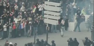 Multidão de jovens estudantes e manifestantes reunidos em uma grande avenida na França, segurando faixas e cartazes durante um protesto diurno.