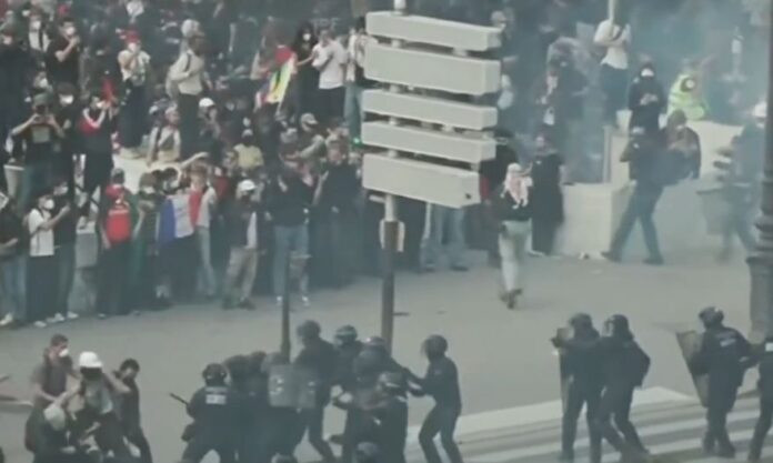 Multidão de jovens estudantes e manifestantes reunidos em uma grande avenida na França, segurando faixas e cartazes durante um protesto diurno.