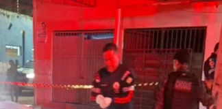 Homem é assassinado a tiros por dupla de moto perto do Mercado do Peixe Profissional do Samu de luvas brancas e policial militar do batalhão de Choque trabalhando em uma cena de crime à noite, com área isolada por fita zebrada.