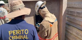 Furto de energia causa rombo de R$ 200 milhões nos cofres públicos de Rondônia Um perito criminal vestindo uma camisa azul escura com o texto "PERITO CRIMINAL" em amarelo acompanha um técnico da Energisa que inspeciona uma caixa de energia.