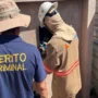 Um perito criminal vestindo uma camisa azul escura com o texto "PERITO CRIMINAL" em amarelo acompanha um técnico da Energisa que inspeciona uma caixa de energia.