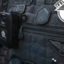Três suspeitos morrem em tiroteio com a Polícia Militar durante assalto em São Paulo Colete tático escuro de um agente da Polícia Militar de São Paulo, equipado com uma câmara corporal (bodycam) e ostentando as insígnias oficiais da corporação.