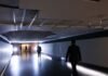 Parte do teto desaba no “Túnel do Tempo” da Câmara dos Deputados Corredor do Túnel do Tempo na Câmara dos Deputados com um buraco visível no teto devido à queda do reboco, iluminado por holofotes e com a silhueta de homens a caminhar.