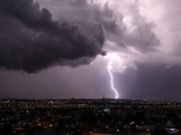 Trovoadas e calor de até 35°C atingem Rondônia e estados vizinhos nesta quarta-feira (28) Céu noturno coberto por nuvens escuras de tempestade sobre uma cidade, com um raio forte caindo e iluminando o horizonte.